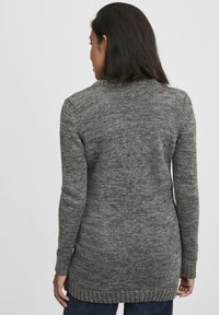 Langer grauer Strickpullover mit strukturiertem Muster, gerippten Bündchen und Saum. Verfügt über eine lockere Passform, die bis zur Mitte des Oberschenkels reicht.