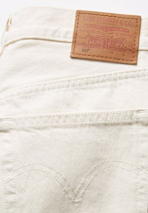 White denim with a leather label featuring embossed text, including "LEVI STRAUSS & CO.," and detailed stitching on the back pockets.