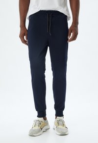 Marine joggingbroek van zachte, gestructureerde stof, met een elastische tailleband met trekkoord, zijzakken met ritssluiting en aansluitende boorden.
