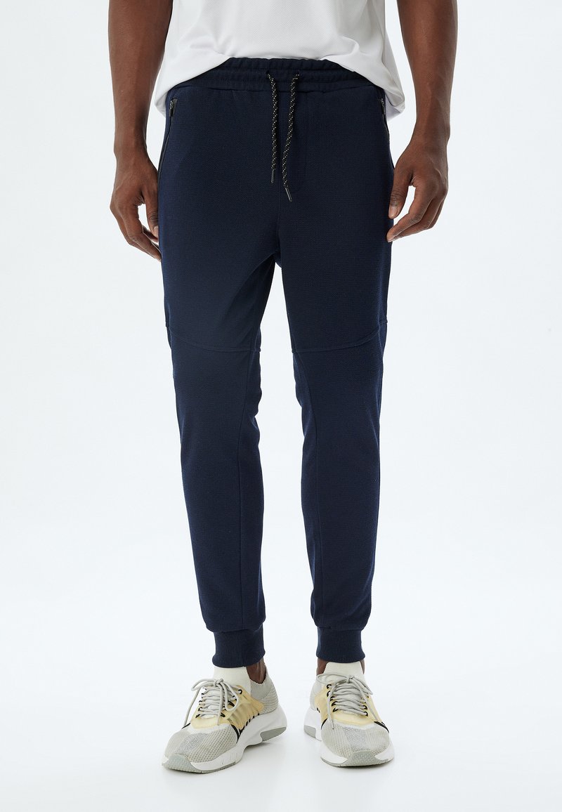 Marine joggingbroek van zachte, gestructureerde stof, met een elastische tailleband met trekkoord, zijzakken met ritssluiting en aansluitende boorden.