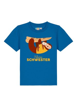 Blau katoenen t-shirt met een luiaard die aan een tak hangt, met de tekst "Kleine Schwester" in het geel onder de illustratie.