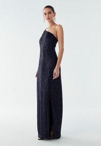 Námornícky modré, flitrové, dlhé šaty až po zem s jedným ramienkom a rozparkom po stehná; hladká textúra a priliehavý strih.