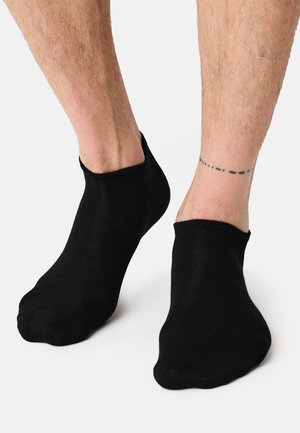 Sorte ankelstrømper lavet af et strækbart, let materiale. Glat tekstur med en ribbet manschette og sømløs tådesign.