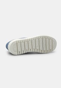 Kék velúr sneaker fehér gumitalppal. A talp mintázott felülete tapadást biztosít. A dizájn alacsony kivágású, lekerekített szélekkel rendelkezik.