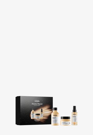 Set von Haarreparaturprodukten in einer schwarzen Box mit goldenen Akzenten. Enthält zwei Flaschen und ein Glas, mit Etiketten und einem eleganten Design.