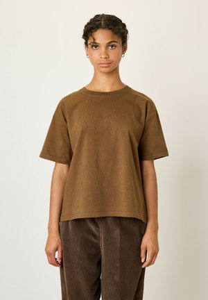 T-shirt brun à manches courtes côtelé avec un col rond, offrant une coupe décontractée et une texture douce, associé à un pantalon en velours côtelé brun.
