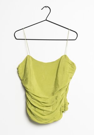 Grüner, strukturierter Oberteil mit verstellbaren Spaghettiträgern, der ein gerafftes Stoffdesign und einen Rüschensaum aufweist. Hängt an einem schwarzen Metallkleiderbügel.