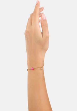 Bracciale in oro con una pallina rosa rotonda e un piccolo ciondolo pendente, indossato su una mano sollevata con unghie naturali.