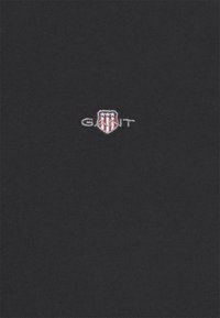 Black fabric with a small embroidered GANT shield logo featuring red and white stripes and three white stars above.