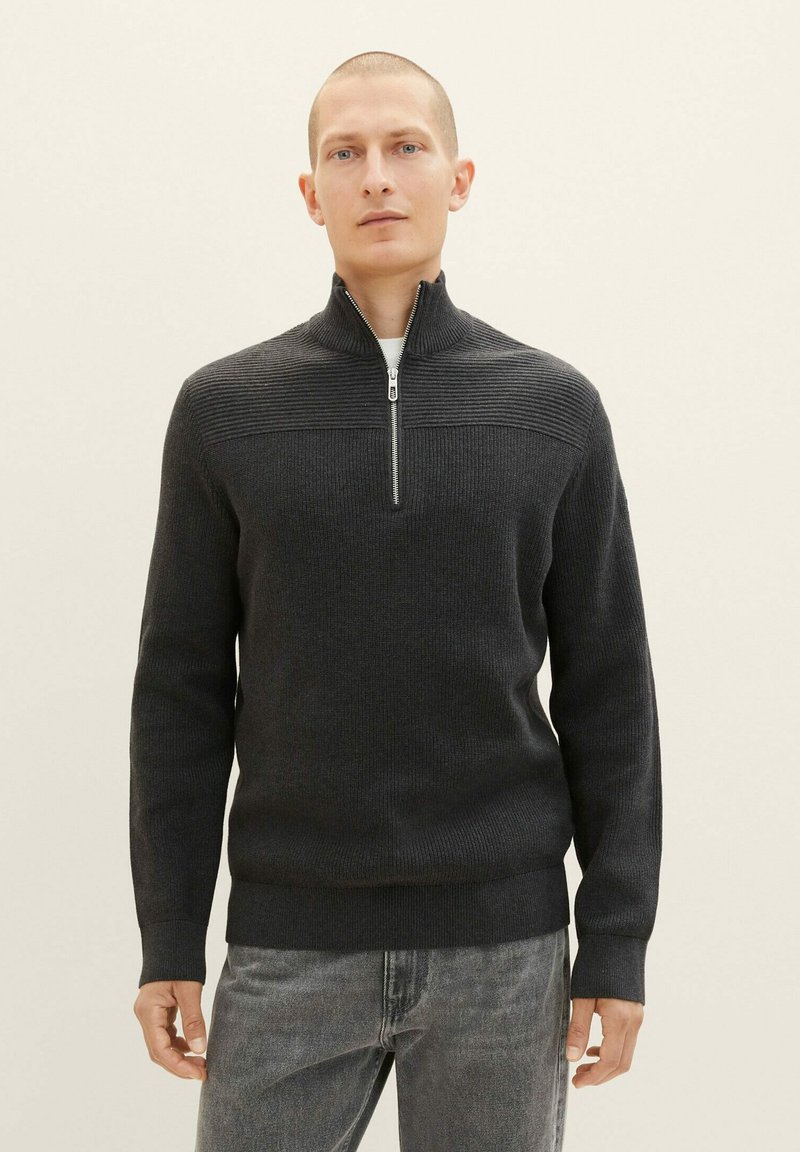 Dunkelgrauer gestrickter Pullover mit hohem Kragen und halberReißverschluss, der über strukturierte Rippen an den Schultern und eine taillierte Silhouette verfügt.