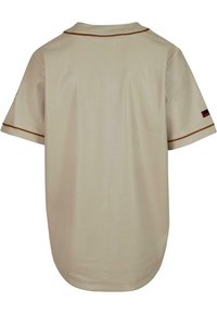 Camicia a maniche corte in rete beige chiaro con piping marrone, dotata di colletto e orlo arrotondato. Include un piccolo logo sullo manica sinistra.