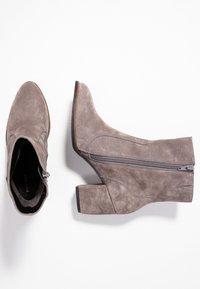 Szare zamszowe botki za kostkę z blokowym obcasem, spiczastym noskiem, detalem zamka błyskawicznego z boku oraz przeszyciami. Gładka tekstura i nowoczesny design.