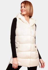 Gilet en duvet léger couleur crème, avec capuche, design matelassé, deux poches frontales avec boutons et une fermeture éclair de chaque côté pour l'ajustabilité.