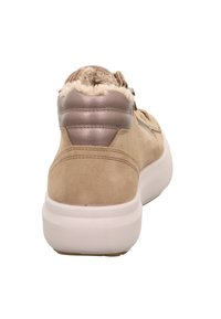 Beige Wildleder-Sneaker mit weißer Sohle, metallischem Fersenpatch und Fleece-Futter, von hinten betrachtet.