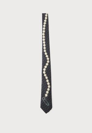 Schwarze Krawatte mit diagonalem Perlenhalsband und silberner Sicherheitsnadel nahe der Spitze befestigt vor einem einfarbigen weißen Hintergrund.