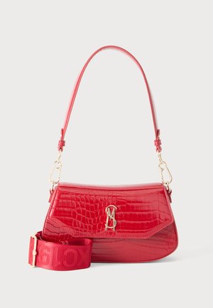 Sac à épaule en cuir rouge texturé avec fermoir doré et bandoulière large en tissu détachable reposant à côté sur fond blanc.
