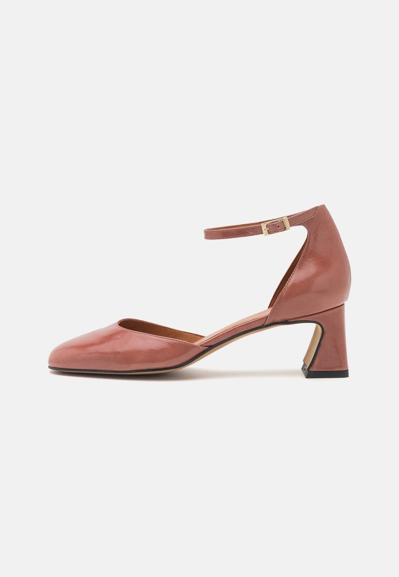 Chaussure en cuir marron à talon moyen avec bride à la cheville et boucle dorée, bout arrondi, et talon épais légèrement évasé sur fond blanc.