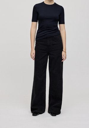 Mustiin, lyhythihainen, istuva toppi yhdistettynä leveälahkeisiin mustiin farkkuihin, jotka on valmistettu denimitilkusta, sileä pinta ja klassinen viisitaskumalli.