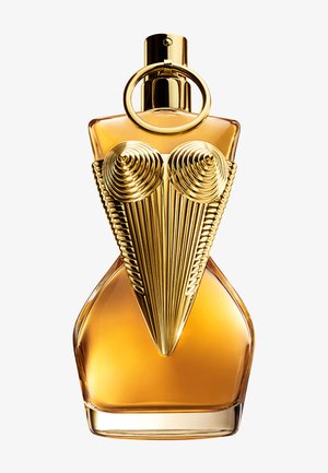 Botella de perfume ámbar curva con forma de torso, adornada con un diseño metálico dorado texturizado que recuerda a un corsé tipo bustier.
