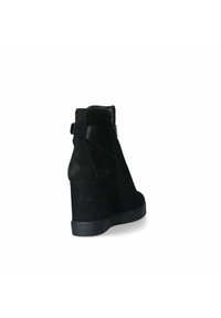 Stivale alla caviglia in suede nero con tacco a wedge, rifinito con texture, cerniera posteriore e accenti hardware neri a contrasto. Design di altezza media.