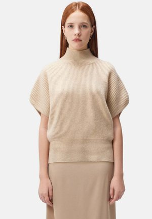 Beige gerippter Strickpullover mit hohem Kragen und kurzen Ärmeln, in lockerem Schnitt und weicher Textur, kombiniert mit einem beigen Rock.