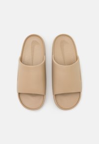Tan slide sandals with a wide strap and textured footbed. Made of smooth synthetic material. Features subtle logo detail on the side.