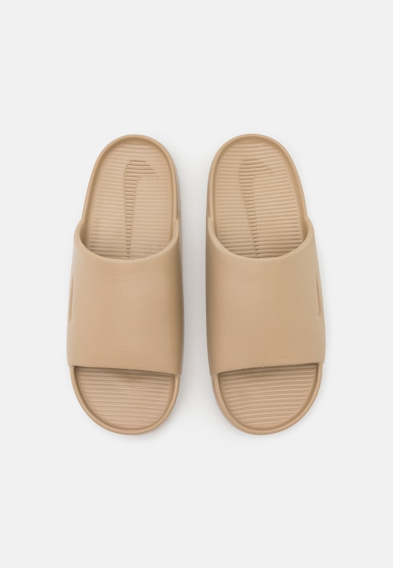 Sandales à glisser beiges avec une large sangle et une semelle intérieure texturée. Fabriquées en matériau synthétique lisse. Présentent un logo discret sur le côté.