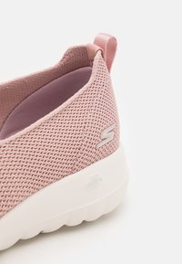 Világos rózsaszín hálós slip-on cipő párnázott gallérral, fehér gumitalppal és ezüst logóval az oldalán. Simább belső bélés.
