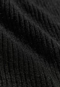 Černá žebrovaná tkanina s měkkým, strukturovaným povrchem, který má jemný lesk a subtílní variace v hloubce. Vhodné pro oděvy nebo doplňky.