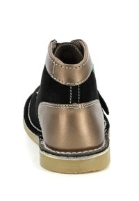 Stivaletto in suede nero con tacco in bronzo metallizzato, cuciture bianche a contrasto e un accento verde vicino alla caviglia. Sole in gomma. Misura 37.
