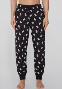 Pantalones de pijama negros con un patrón de palomitas de maíz en rojo y blanco, que cuentan con una cinturilla elástica, tobillos acampanados y una textura suave.
