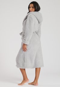 Robe en polaire grise douce avec une texture duveteuse, capuche et ceinture à nouer. Elle possède des manches longues et arrive à mi-mollet pour plus de chaleur et de confort.