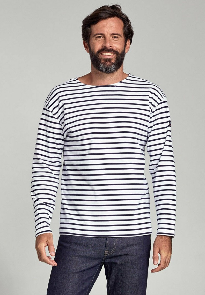 Langærmet, hvid bomulds skjorte med marineblå vandrette striber, med en bred udskæring og afslappet pasform. Bæres med mørk denim jeans.