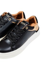 Sneaker in pelle nera con suola bianca, foderatura interna color beige, lacci neri e occhielli dorati, esposti su uno sfondo bianco.