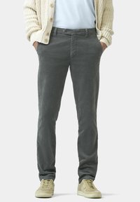 Graue Baumwollhosen mit geradem Bein, ausgestattet mit einem Knopfverschluss und Taschen, kombiniert mit hellen Sneakers.
