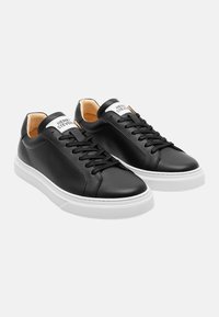 Black leather sneakers with white rubber soles, lace-up design, smooth texture, and branded tab at the heel featuring "HENRY STEVEN."