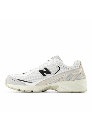 Weißer und beiger Sportschuh mit Mesh-Gewebe, gepolsterter Sohle und schwarzem "N"-Logo an der Seite, im Profil vor weißem Hintergrund gezeigt.