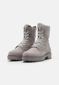 Bottines en suede grises avec bouts ronds, semelles en caoutchouc plates, fermeture à lacets à l'avant et fermeture éclair sur le côté. Comprend des accents texturés et des coutures contrastantes.