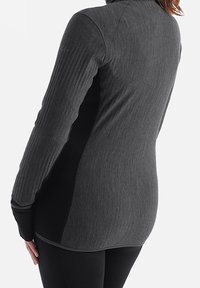 Camiseta atlética de manga larga en negro y gris oscuro con textura acanalada, cuello alto y diseño ajustado. Las mangas tienen orificios para los pulgares para mayor cobertura.