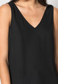 Top senza maniche nero con scollatura a V, tessuto liscio e cuciture pulite; senza motivi o decorazioni visibili.