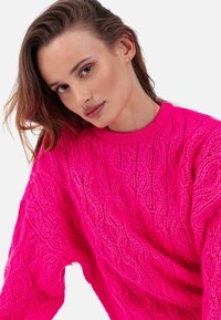 Leuchtend pinker Strickpullover mit strukturierter Optik, mit geripptem Halsausschnitt und lockerem Schnitt. Weiches, grob gestricktes Material.