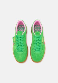 Zelené semišové sportovní boty s růžovými akcenty, s plochými tkaničkami, gumovými podrážkami a vzorovanou stélkou. Značka na boku.