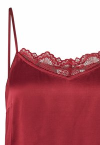 Siidist top sügavpunases toonis reguleeritavate spagetirihmadega ja õrnade laineliste pitsääreline kaelusel. Sile tekstuur.