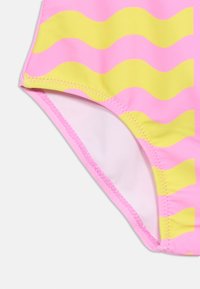 Κάτω κοντινή λήψη ροζ και κίτρινου μαγιό με κυματιστές ρίγες και ζιγκ ζαγκ ραφή σε λεία ύφασμα.