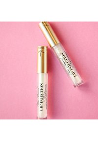 Twee lipgloss-tubes op een roze achtergrond. De ene is helder met gouden accenten; de andere heeft een gouden dop en zwarte letters, wat aangeeft dat het om lipplumper gaat.