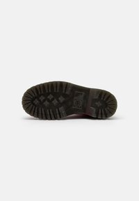 Suola di scarpa con scanalature profonde, realizzata in gomma. Presenta un design di grip a motivo e un colore nero solido con accenti rialzati sui lati.