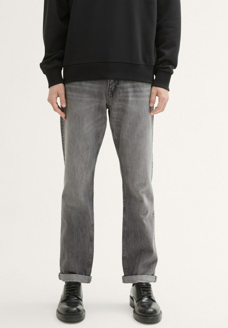 Szare dżinsy z luźnym krojem, z podwiniętymi nogawkami i delikatnym przetarciem. W połączeniu z czarnymi butami i czarną bluzką z długim rękawem.