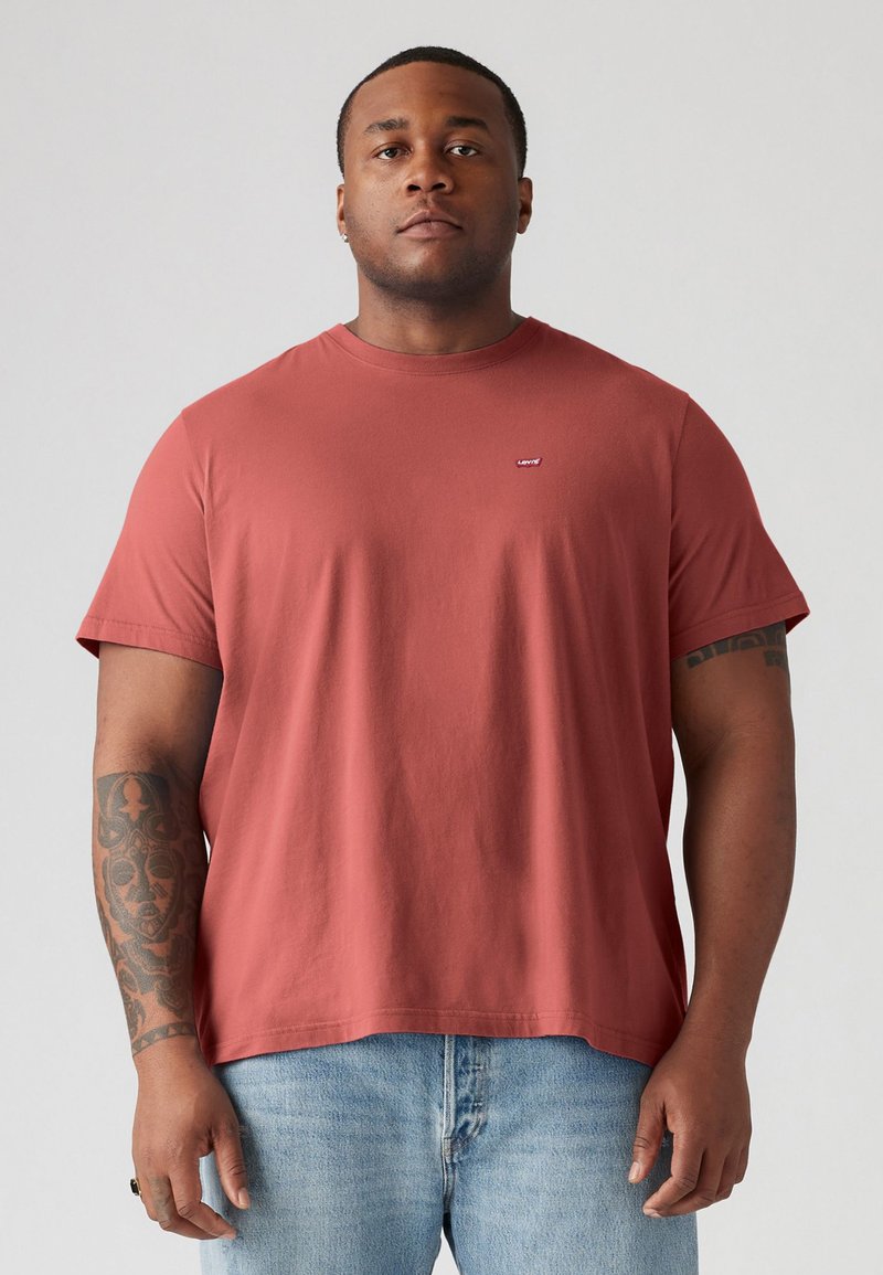Rode t-shirt met korte mouwen en ronde hals, gemaakt van zachte katoen, met een klein Levi's logo op de borst, gecombineerd met lichtblauwe jeans.