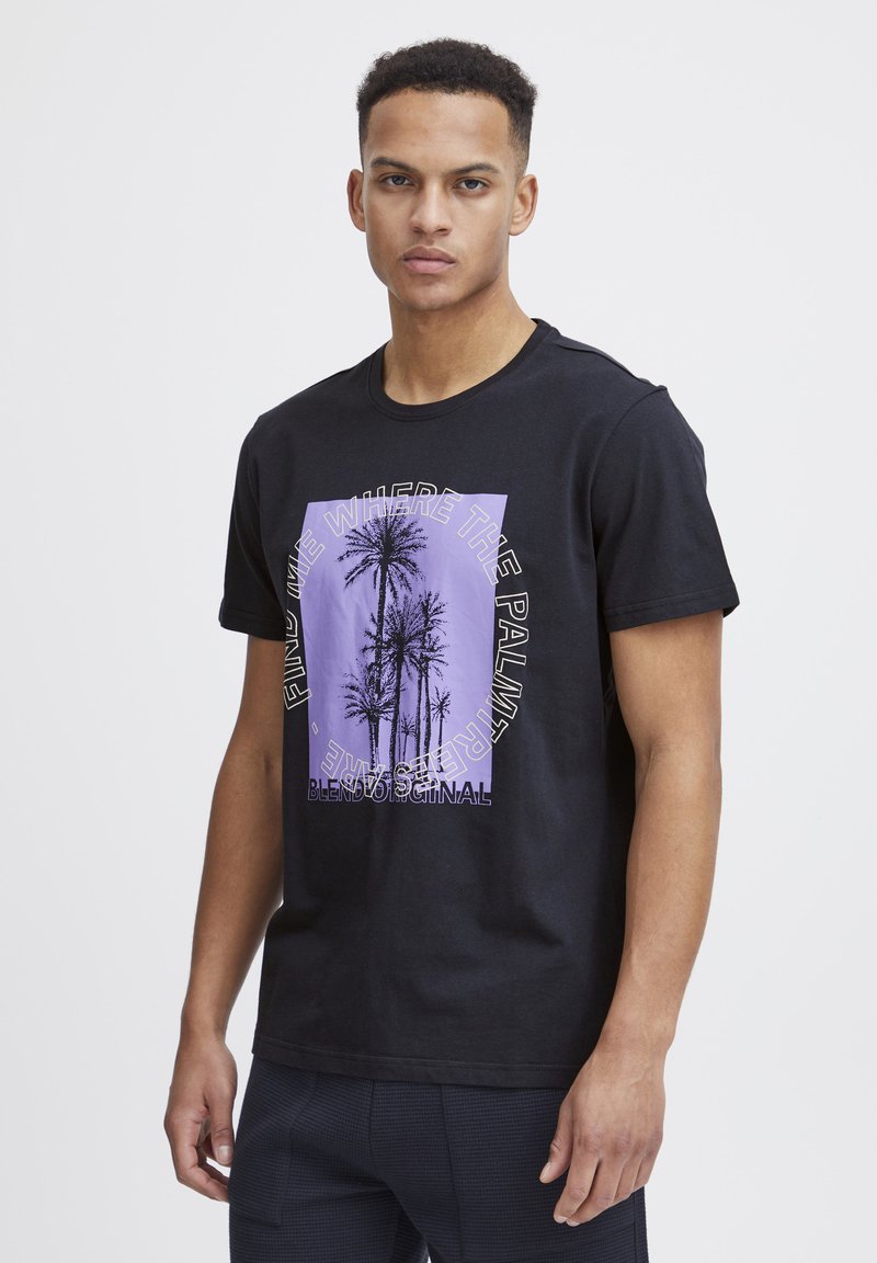 Camiseta de algodón negra con un gráfico morado de palmeras y elementos de texto. Con mangas cortas y un cuello redondo. Textura suave.