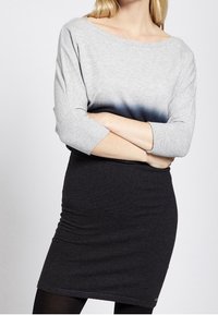 Grauer Stricktop mit Dreiviertelärmeln, der zu dunkelblau verblasst; kombiniert mit einem enganliegenden schwarzen Rock. Dehnbarer Stoff, einfaches Design.